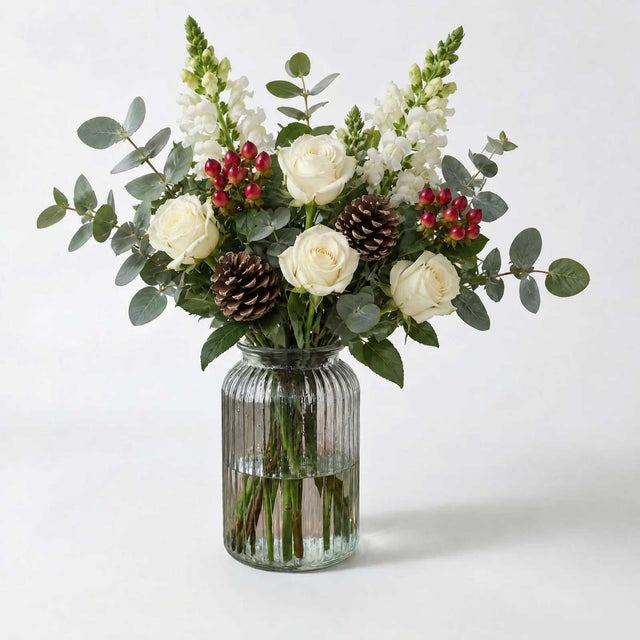 The Dew letterbox bouquet in a vase, white roses, hypericum berries, eucalyptus, snapdragons and pine cones