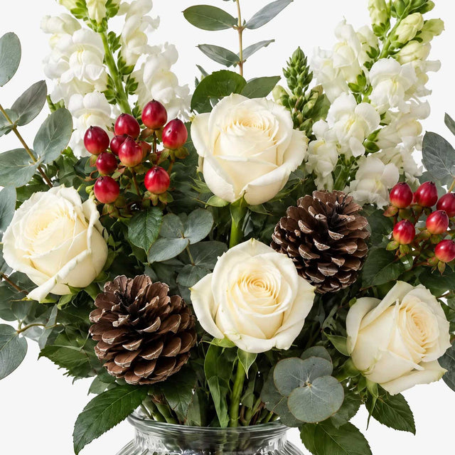 Close-up of white roses and hypericum berries among eucalyptus leaves in The Dew bouquet