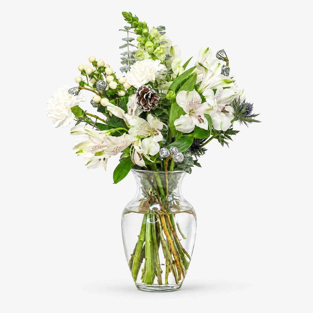 White Christmas flowers with pine cones and eucalyptus arranged in a vase