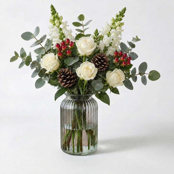 The Dew letterbox bouquet in a vase, white roses, hypericum berries, eucalyptus, snapdragons and pine cones