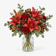 The Mulberry Christmas bouquet of red lilies, carnations and hypericum berries with eucalyptus in a vase.