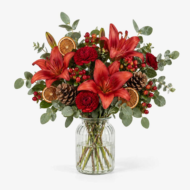 The Mulberry Christmas bouquet of red lilies, carnations and hypericum berries with eucalyptus in a vase.